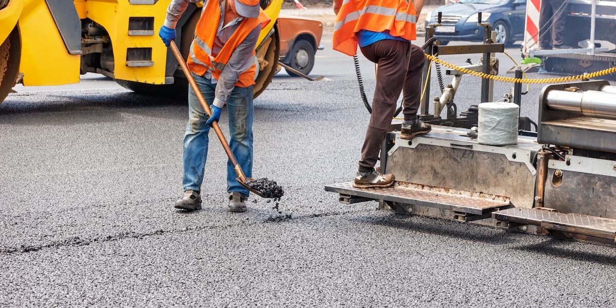 Workers paving a road with asphalt.