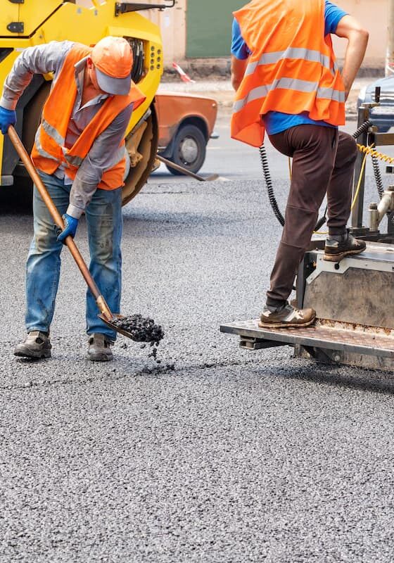 Workers paving a road with asphalt.